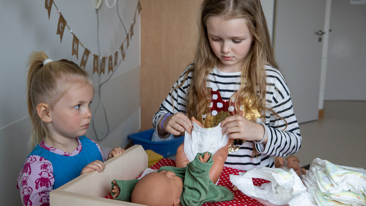 Zwei Kinder spielen mit einer Puppe